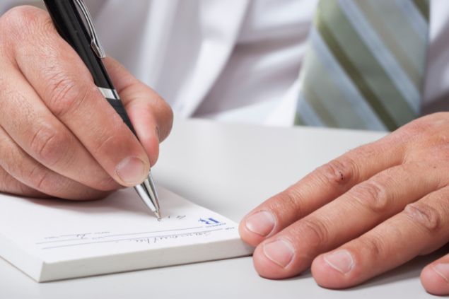 Imagem só das mãos de um médico prescrevendo medicação