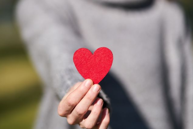 Imagem de uma mulher segurando um coração feito de papel