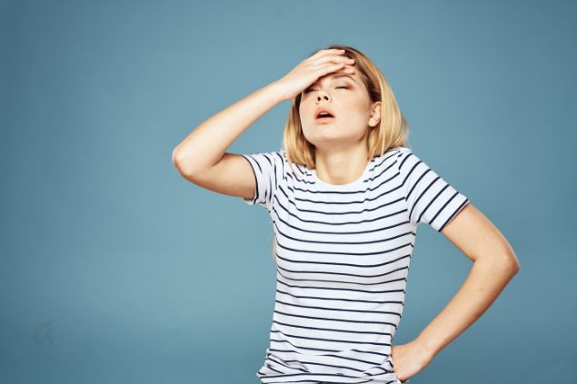 Imagem de uma mulher expressiva, com a mão na cabeça como se estivesse cansada