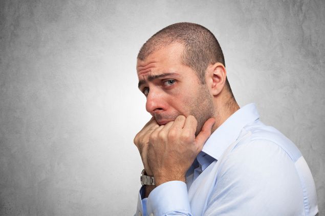 Imagem de um homem com expressão de insegurança e medo em um fundo acinzentado