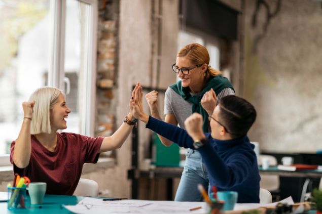 Imagem de uma pessoa incentivando mais duas em um escritório, todos estão sorrindo