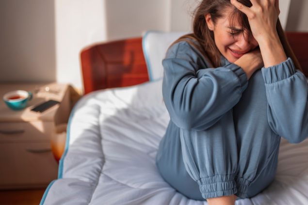 Imagem de uma mulher com ansiedade sentada na cama