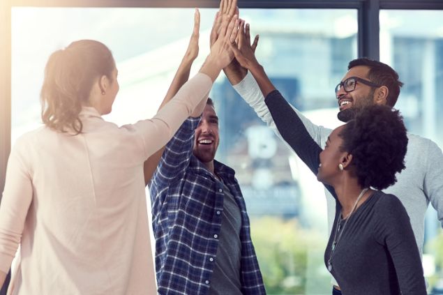 Imagem de uma equipe no trabalho comemorando 