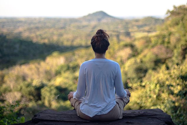 Mulher meditando com a vista de montanhas e floresta