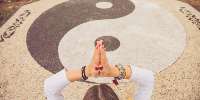 Mulher meditando em frente ao símbolo yin yang