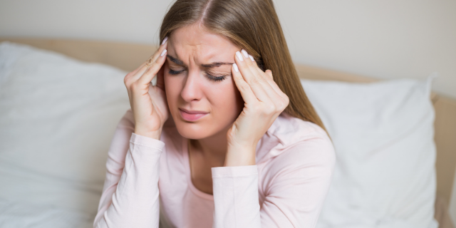 Mulher pressiona as têmporas em sinal de dor.