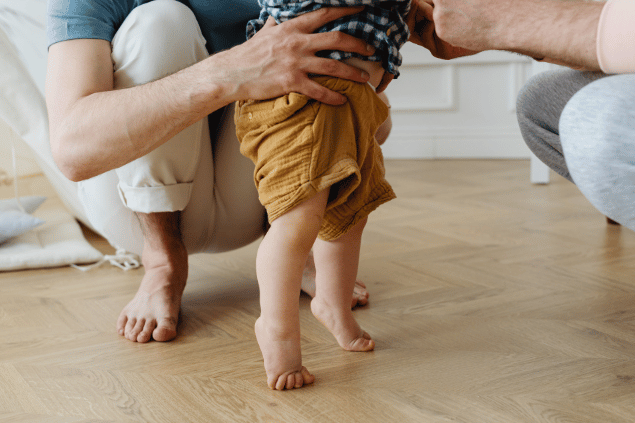 Karolina Grabowska / Pexels / Canva Pro Uma pessoa segurando um bebê enquanto aprende a caminhar.