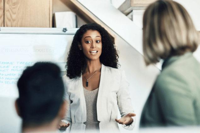Reunião de apresentação de projeto profissional. Uma mulher assume posição de liderança e discursa sobre a ideia. 