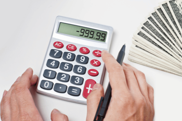 Pessoa em débito fazendo contas na calculadora. 