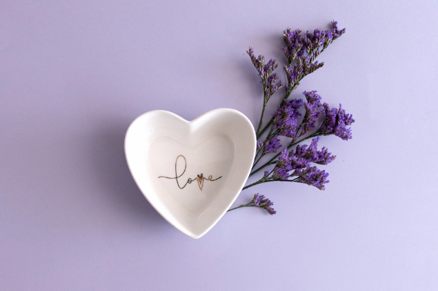 Um prato branco em formato de coração ao lado de flores de lavanda