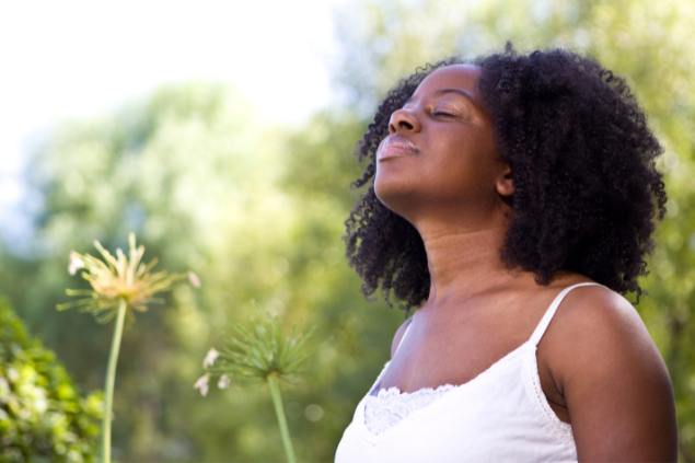 Mulher negra de olhos fechados em um campo com flores