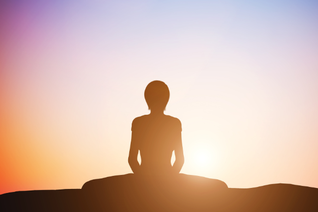 Silhueta de uma mulher e ao fundo, o pôr do sol