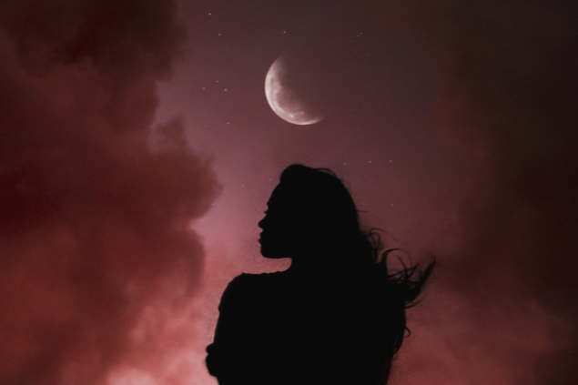 Silhueta de uma mulher e ao fundo, a lua crescente
