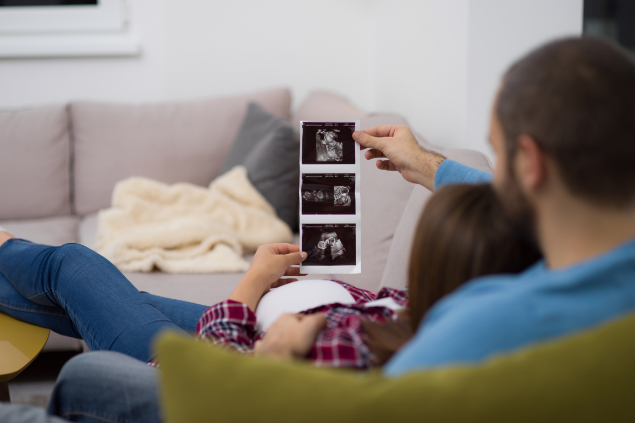 Casal vendo as fotografias do ultrassom de seu bebê
