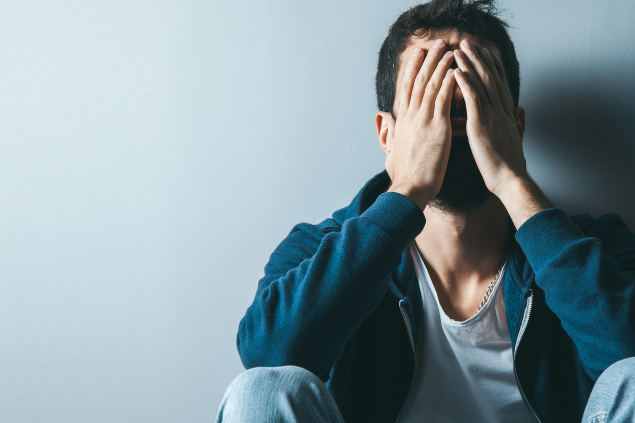 Homem sentado com as mãos no rosto
