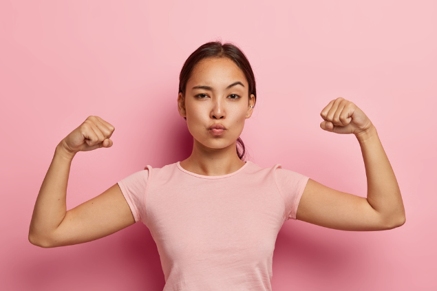 Mulher asiática mostrando os muques 