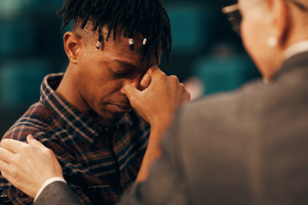 Homem chorando enquanto é consolado por outro