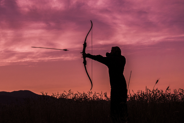 Silhueta de pessoa atirando com arco e flecha