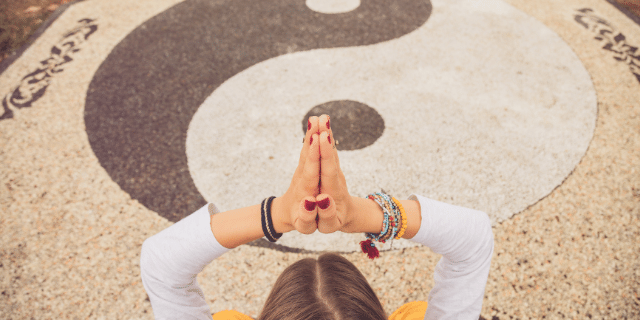 Imagem de uma mulher com as mãos para o alto com o símbolo Yin Yang no chão. 