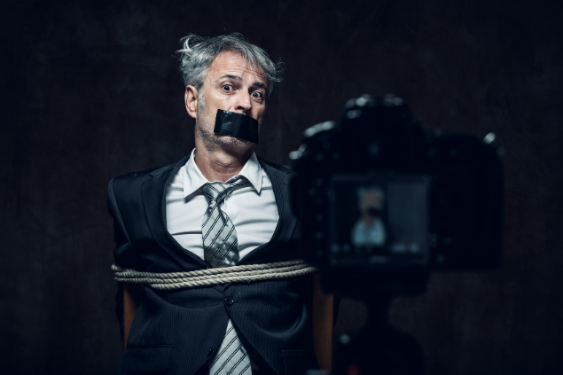 Homem sendo feito de refém enquanto é filmado