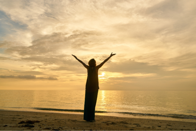 Pessoa andando na praia de braços abertos