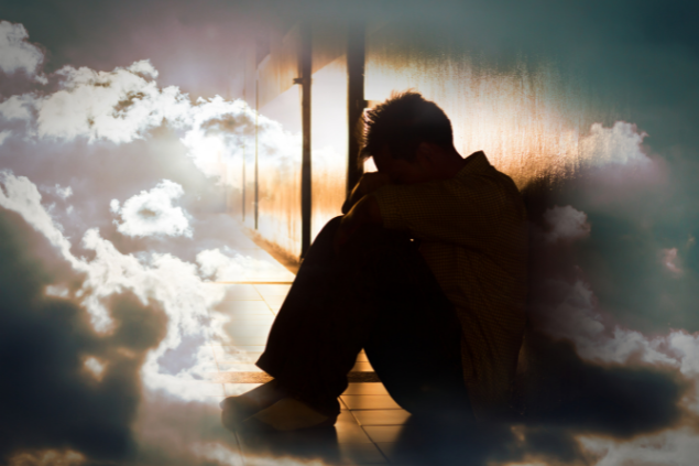 Pessoa sentada com o rosto entre seus joelhos