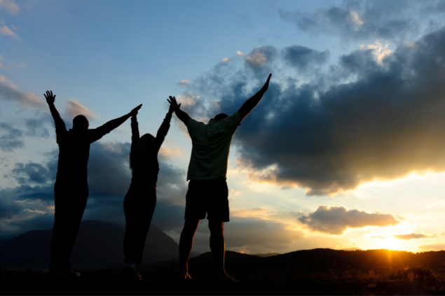 Silhueta de 3 pessoas e ao fundo o céu com nuvens