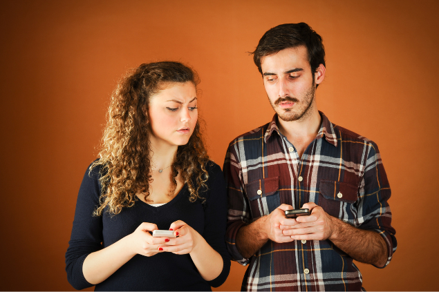 Casal desconfiado, olhando o celular um do outro