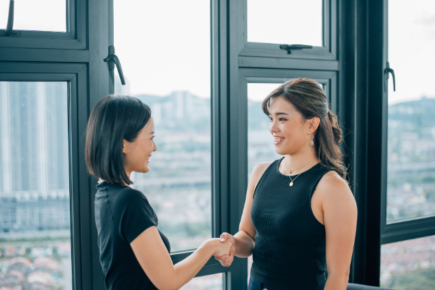 Duas mulheres apertando as mãos e sorrindo