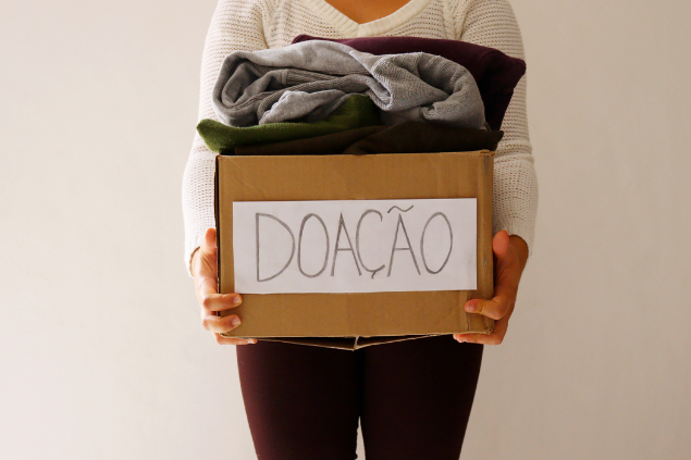 Mulher segurando caixa com doações dentro e em cima