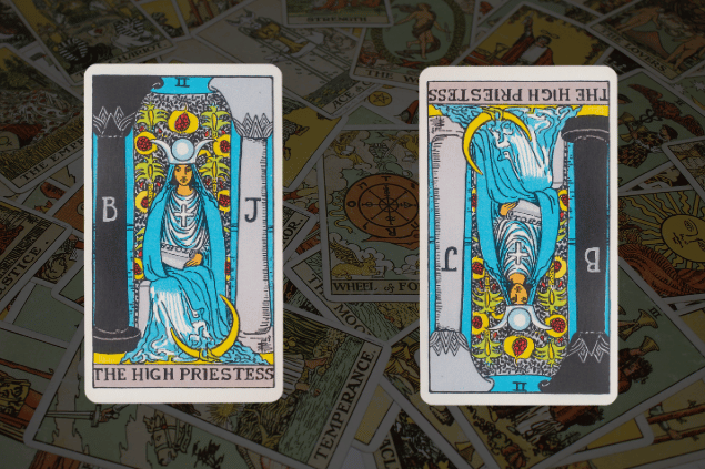 Montagem com a carta A Sacerdotisa do Tarot na posição normal e outra carta A Sacerdotisa na posição invertida. Ao fundo, há várias cartas de Tarot.