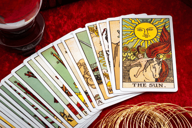 Uma sequência de cartas de um baralho de tarot estão dispostas sobre uma mesa vermelha.