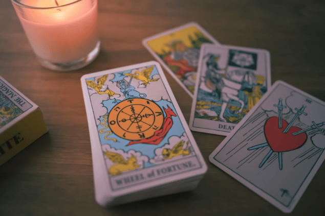 Quatro cartas de tarot e um baralho estão dispostos em uma mesa.