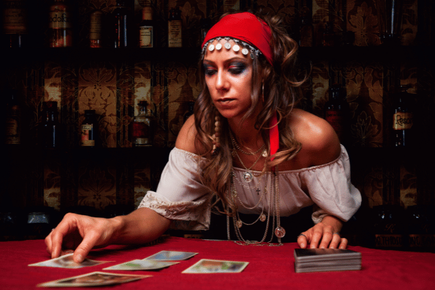 Uma cigana está colocando cartas de Tarot sobre uma mesa.