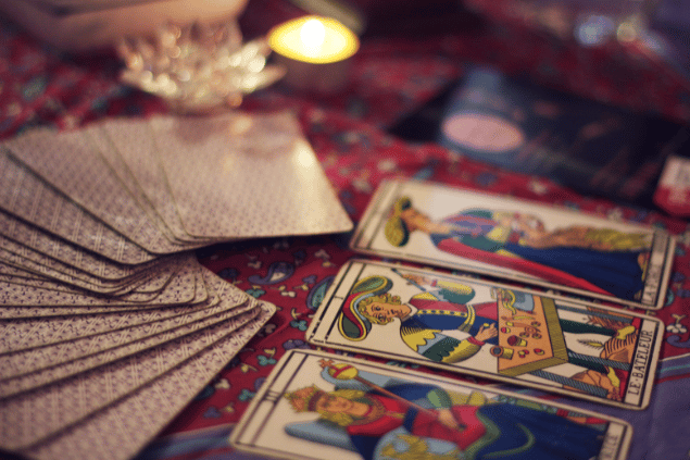 Três cartas e mais um baralho de Tarot estão sobre uma mesa e no foco da imagem.