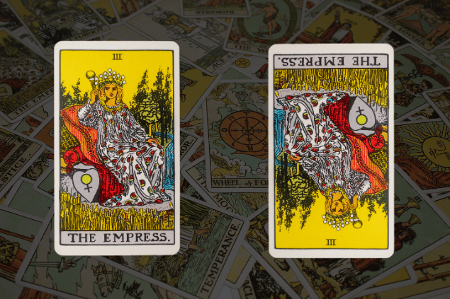 Montagem com a carta A Imperatriz do Tarot na posição normal e outra carta A Imperatriz na posição invertida. Ao fundo, há várias cartas de Tarot.