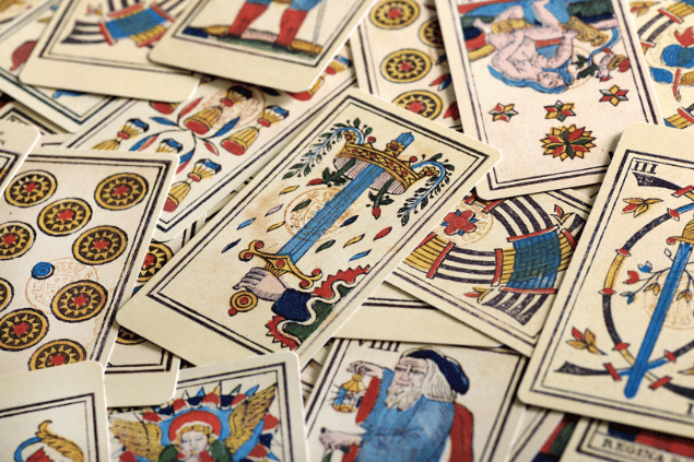 Várias cartas de Tarot estão espalhadas e desordenadas umas sobre as outras sobre uma superfície.