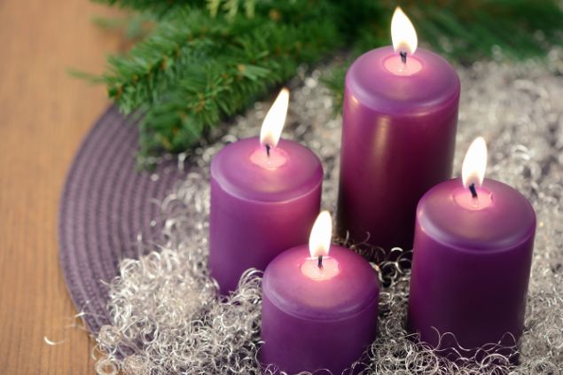 Imagem de quatro velas roxas, acesas, representando uma das oferendas feitas para a pombagira Rosa Caveira.