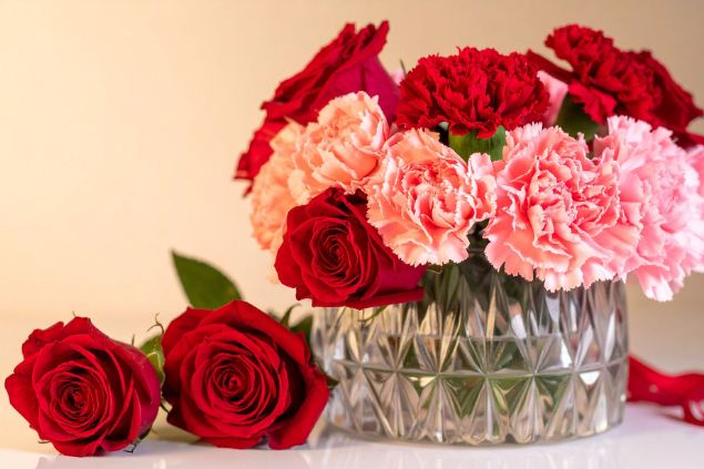 Imagem de um vaso de vidro contendo rosas vermelhas e cravos na cor rosa, simbolizando uma das oferendas para a Pombagira Cigana.
