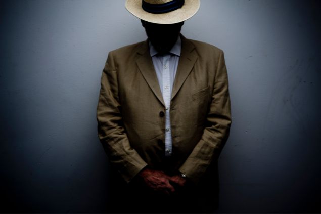 Imagem de um homem misterioso, usando um terno marrom e um chapéu panamá, simbolizando a entidade Zé do Morro.