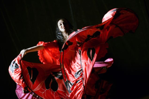 Imagem de uma cigana usando um lindo vestido vermelho com detalhes pintados na cor preta. Ela simboliza a Cigana Carmencita da Umbanda.