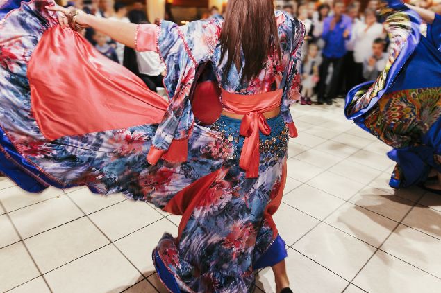 Imagem de uma mulher usando um vestido florido em azul e vermelho, dançando em um terreiro, simbolizando a cigana Carmencita da Umbanda.