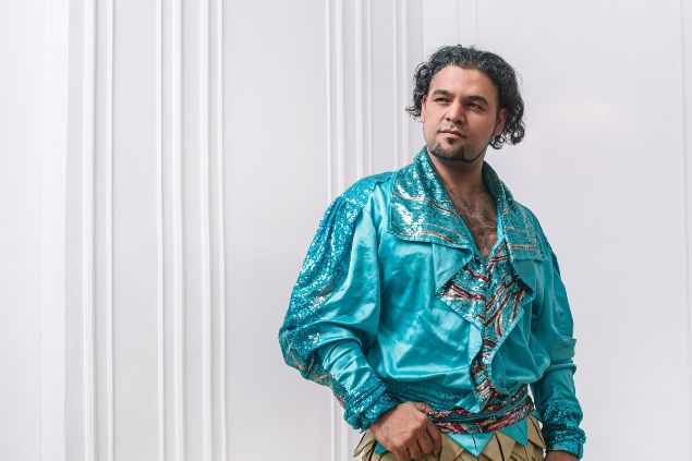 Imagem de um homem, vestindo uma camisa azul claro com adornos nas cores prata e dourado, simbolizando o cigano Igor da Umbanda.