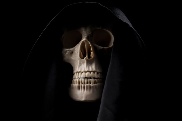 Imagem da ossada de um crânio  usando uma capa preta, simbolizando o Exu da Morte.