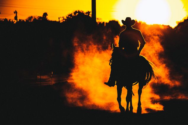 Imagem de um homem montado em um cavalo, em uma tarde com um lindo pôr do Sol, simbolizando a entidade João Boiadeiro na Umbanda.