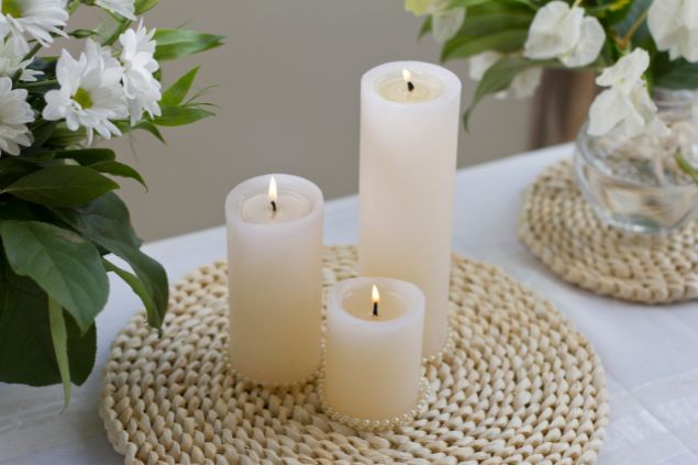 Imagem de três velas brancas acesas em um altar, simbolizando uma das oferendas para o Pai João da Umbanda.