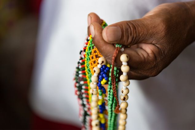 Imagem da mão do caboclo Pena Vermelha da Umbanda, segurando várias guias.