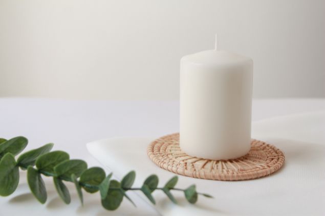 Imagem de uma vela branca e de um galho de uma erva espiritual, simbolizando uma oferenda para o pai Francisco da Umbanda.