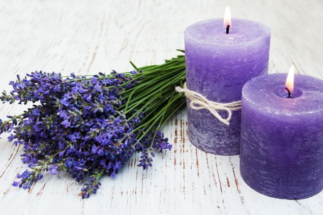 Almaje / Getty Images / Canva Imagem de duas velas na cor lilás e um arranjo floral de lavanda também na cor lilás, simbolizando uma das oferendas para a cigana Sara da Umbanda.
