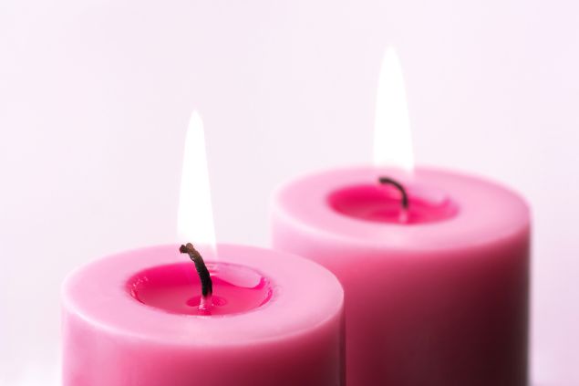 Imagem de duas velas cor de rosa acesas, simbolizando uma das oferendas para a Pombagira Mirim da Umbanda.